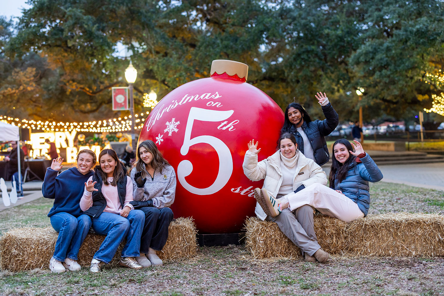 A group of students by the red 5th st. Christmas ornament