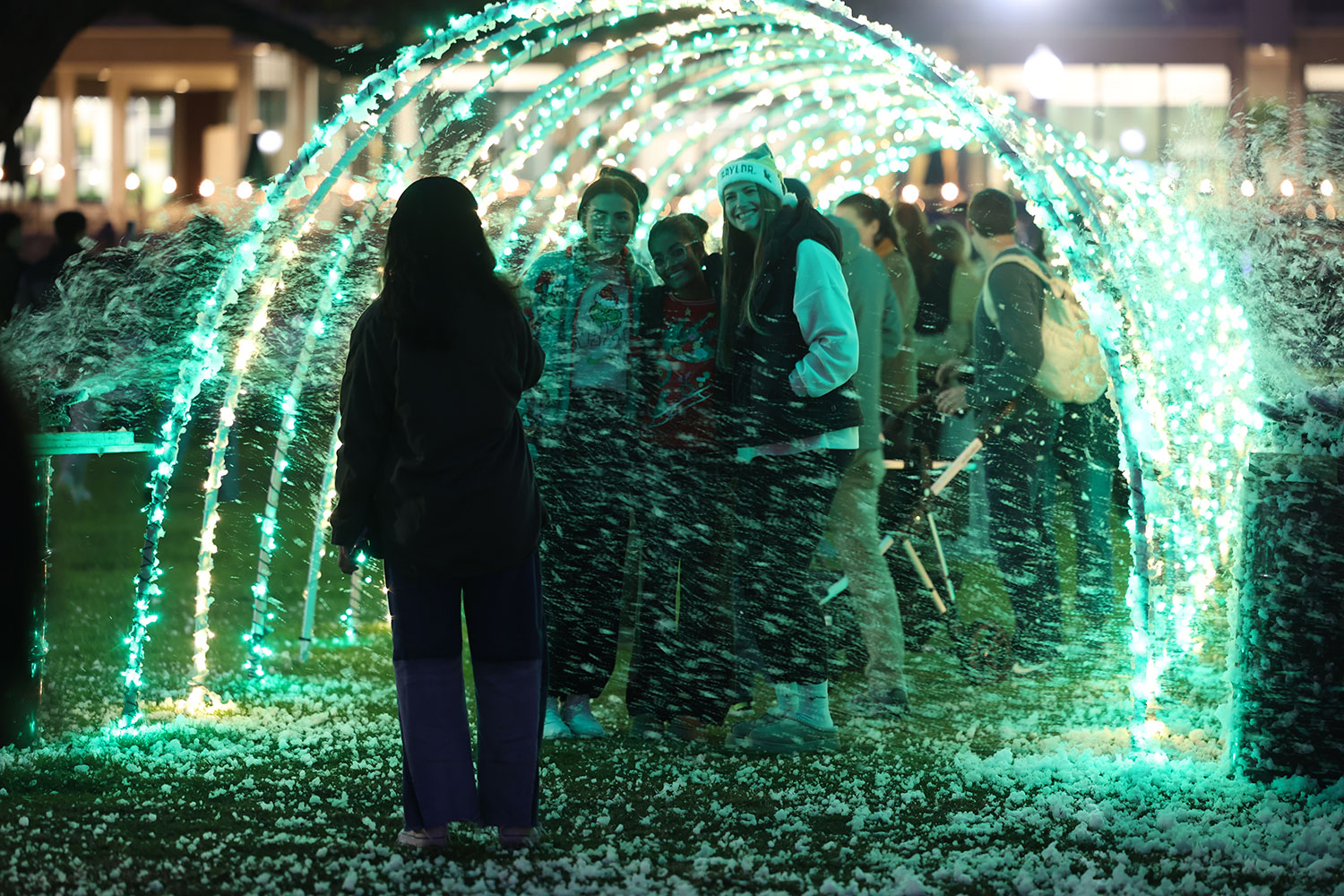 Students standing in a lighted green tunnel