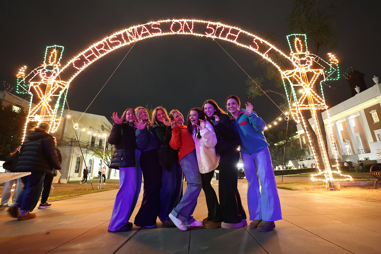 A group of Baylor Students under the lighted Christmas on 5th St. sign